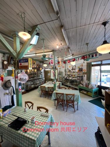 a restaurant with tables and chairs in a room at Dormitory Sandanya Guesthouse in Shirahama