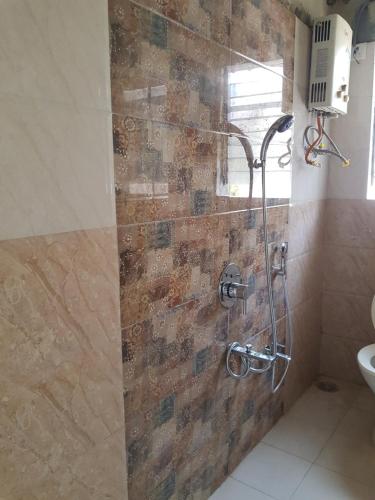 y baño con ducha y pared de piedra. en Hotel Trisha Residency, en Lonavala