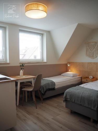 1 dormitorio con 2 camas, escritorio y mesa en Ruchome Piaski, en Łeba