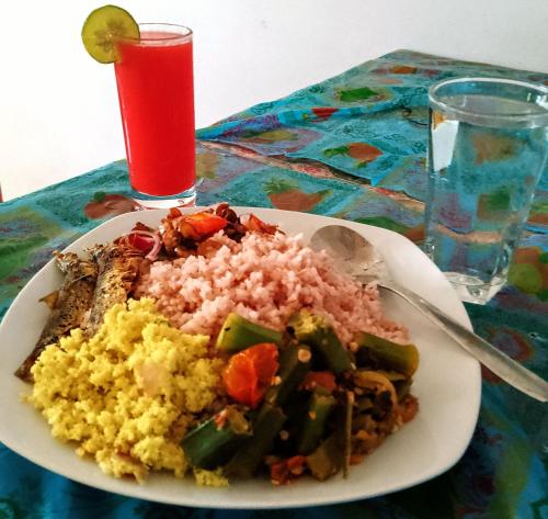 a plate of food with rice and vegetables and a drink at Kalimetiya Beach Cabana in Hungama