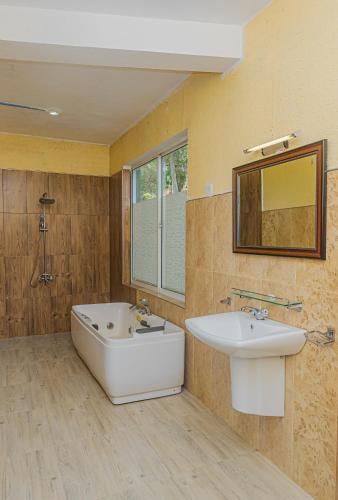 a bathroom with a tub and a sink and a mirror at Ravana Range Ella in Ella