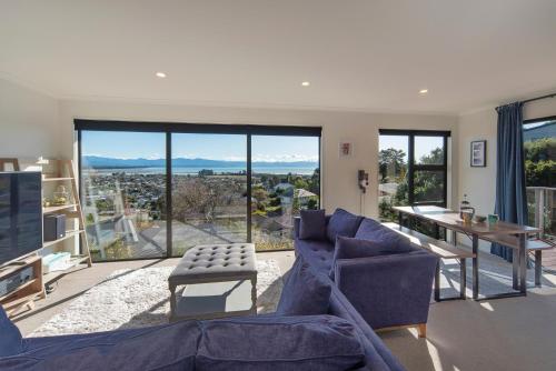 Blue Water Views في نيلسون: غرفة معيشة مع أثاث أزرق ونوافذ كبيرة
