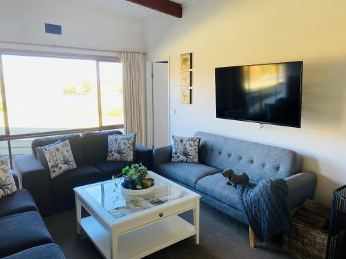 a living room with a blue couch and a tv at ELM Accommodation - Merrijig in Merrijig