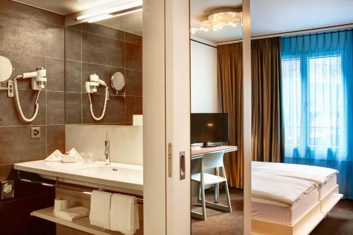 Cette chambre comprend un lavabo et un lit. dans l'établissement Continental Park, à Lucerne