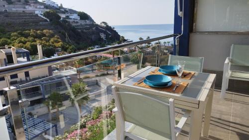 a table and chairs on a balcony with a view of the ocean at Junto al mar y con piscina abierta in Almuñécar
