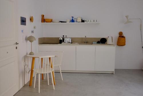- une cuisine avec des placards blancs, une table et des chaises dans l'établissement MILORA SuNSET, à Pollonia