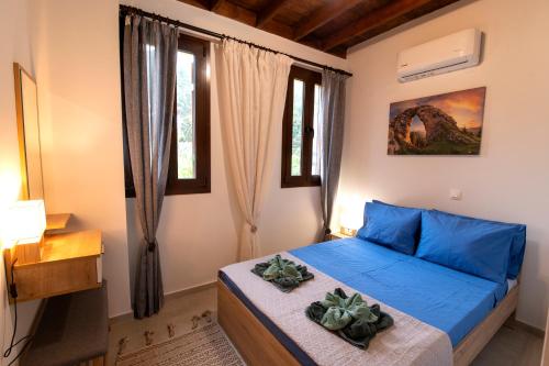 a bedroom with a blue bed and windows at DIMIS ASOMATOS HOMES in Kos