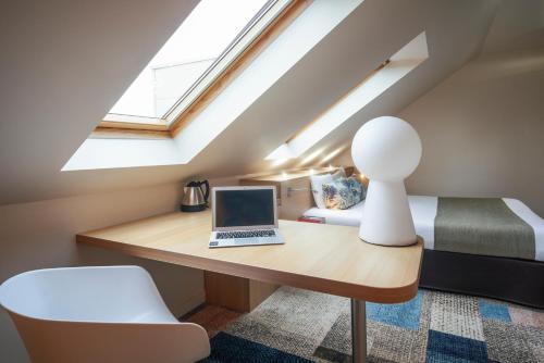 a room with a desk with a laptop and a bed at Kyriad Le Mans Est in Le Mans