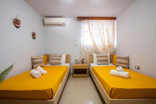 two beds in a room with yellow sheets at Maia Luxury Pool Villa in Afantou