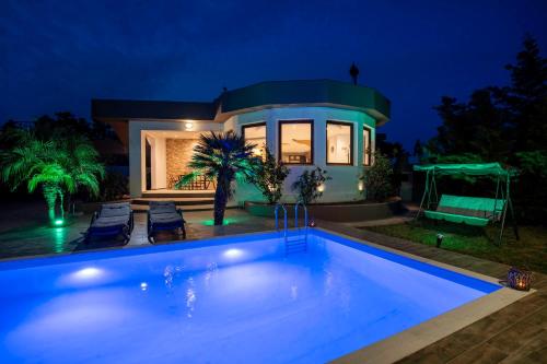 a swimming pool in front of a house at night at Maia Luxury Pool Villa in Afantou