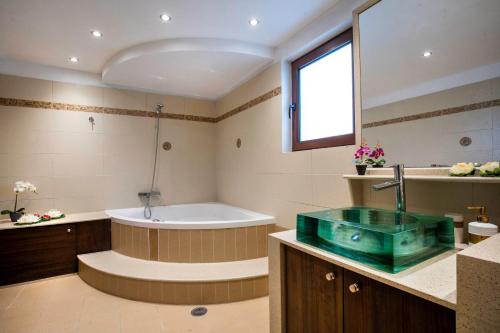 un ampio bagno con vasca e lavandino di Maia Luxury Pool Villa a Afantou