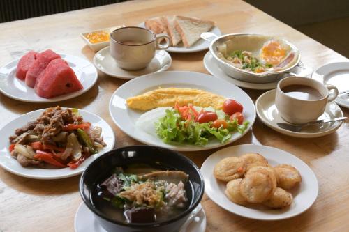Rattana Park Hotel في بيتسانولوك: طاولة مع أطباق من الطعام وأكواب من القهوة
