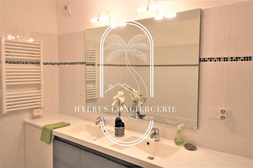 a bathroom with a sink and a mirror at Au bout de la rue la Mer- T3 Jardin Piscine PARKING WIFI BY HC in Carqueiranne