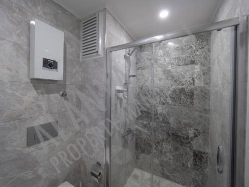 baño con ducha y puerta de cristal en Calypso Residence Luxurious Beachside Apartment in Alanya D6, en Alanya