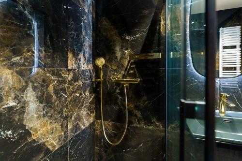 a shower in a bathroom with a black marble wall at Apartament Shellter Sun&Sea Rogowo koło Kołobrzegu_Dźwirzyno_nocleg in Rogowo