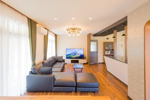 ein Wohnzimmer mit einem Sofa und einem TV in der Unterkunft Misora Yufuin - Vacation villa with private hot spring in Yufu