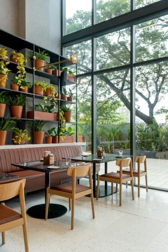 Un comedor con mesas y sillas y grandes ventanales. en Greenpark Bengaluru, en Bangalore