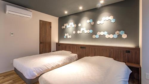 two beds in a room with a wall with clouds at Kissuien Stay&Food in Kyotango