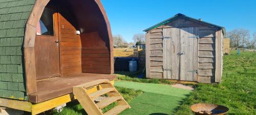 a wooden outhouse and a shed in a yard at Cherry Trees Farm Campsite in Welton