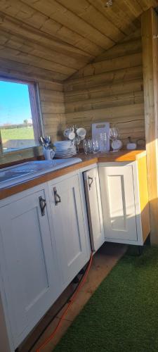 a kitchen with white cabinets and a window in a cabin at Cherry Trees Farm Campsite in Welton