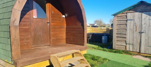 a wooden out house with a wooden door and a bench at Cherry Trees Farm Campsite in Welton