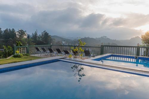 a swimming pool with chairs and a fence at Ravana Range Ella in Ella
