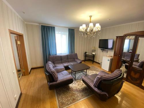 a living room with couches and a table and a television at Hotel Astam in Kostanay