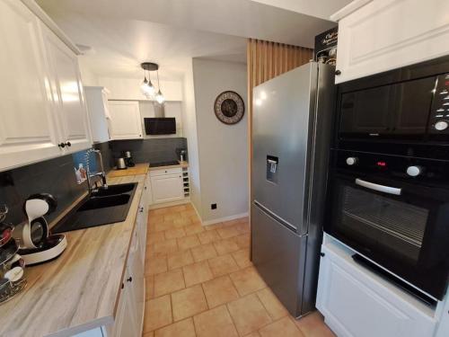 une cuisine avec un réfrigérateur en acier inoxydable et des armoires blanches dans l'établissement Les lits de la Loire, à Saint-Père-sur-Loire