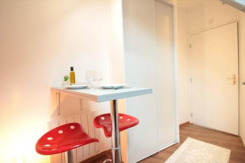 une petite table avec des tabourets rouges dans une pièce dans l'établissement Grenier du Lac 100 m du lac, à Annecy