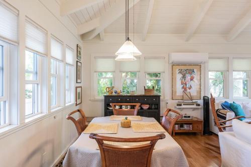 a dining room with a table and some windows at Sunshine Cottage just steps to Kailua beach in Kailua