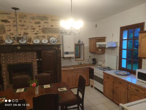 eine Küche mit Holzschränken, einem Tisch und einem Kamin in der Unterkunft Les colombages in Pazayac
