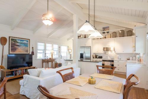 a living room with a white couch and a table at Sunshine Cottage just steps to Kailua beach in Kailua