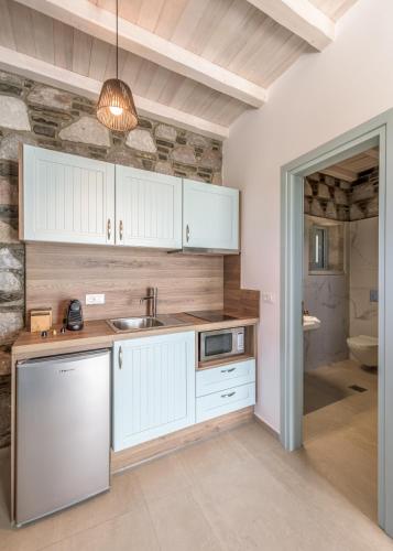 a kitchen with white cabinets and a stone wall at Thea Sunset Suites in Mytakas