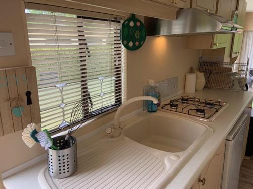 eine Küchentheke mit einer Spüle und einem Herd in der Unterkunft Stacaravan huren in het hart van bosrijk Drenthe op Recreatiepark De Tien Heugten in Schoonloo