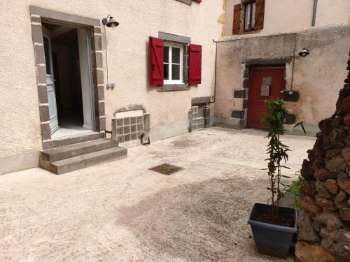 een gebouw met een rode deur en een potplant bij La Lit'Hote in Mirefleurs