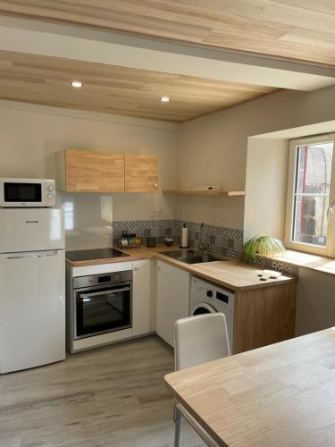 une cuisine avec des appareils blancs et un plafond en bois dans l'établissement La Lit'Hote, à Mirefleurs