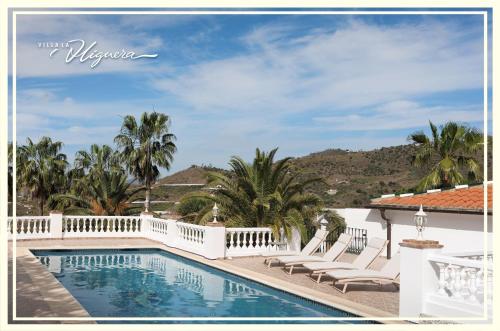 una piscina con sedie a sdraio e una villa di Villa La Higuera a Sayalonga
