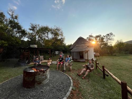 a group of people sitting around a fire pit at Khululeka’s Bush Hut in Millvale
