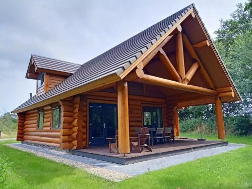 een blokhut met een terras en een schuin dak bij Unieke houten villa met SAUNA in Twente - 5p in Den Ham