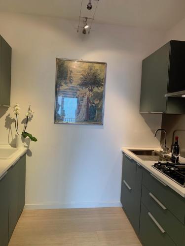 a kitchen with green cabinets and a painting on the wall at Casa Nausica in Acitrezza
