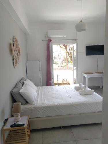 Un dormitorio con una gran cama blanca y una ventana en IOKASTI STUDIOS en Andros