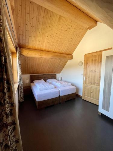a bedroom with two beds and a wooden ceiling at Unieke houten villa met SAUNA in Twente - 5p in Den Ham