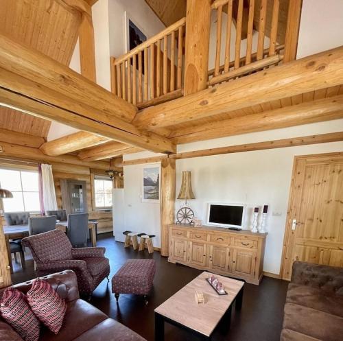een woonkamer met houten plafonds en een woonkamer met een bank bij Unieke houten villa met SAUNA in Twente - 5p in Den Ham