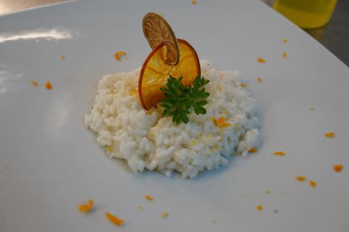 a white plate with rice and an orange on it at Hotel Albatros in Ischia