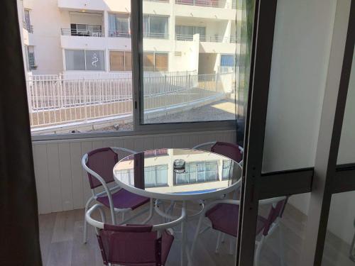 une table et des chaises dans une pièce avec une fenêtre dans l'établissement Appartement en résidence, au Barcarès