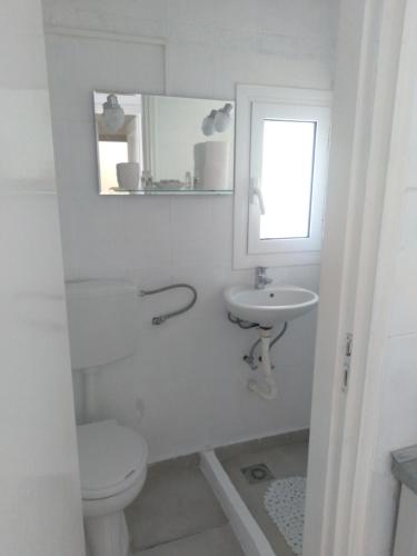 a white bathroom with a toilet and a sink at IOKASTI STUDIOS in Andros