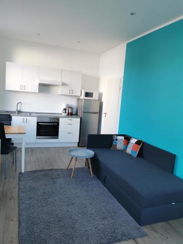 a living room with a blue couch and a kitchen at Nr 1 Ferienwohnung am Teutoburger Wald 