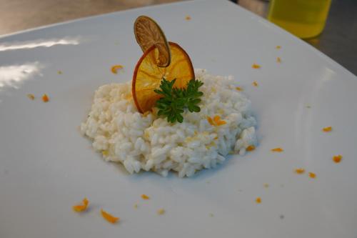 a white plate with rice and an orange on it at Hotel Albatros in Ischia