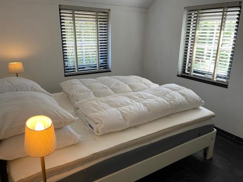 a bedroom with a large white bed with a lamp at RiemersHof in Ermelo