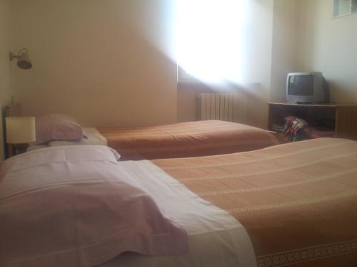 two beds in a hotel room with a tv at La Colombella in Montemonaco